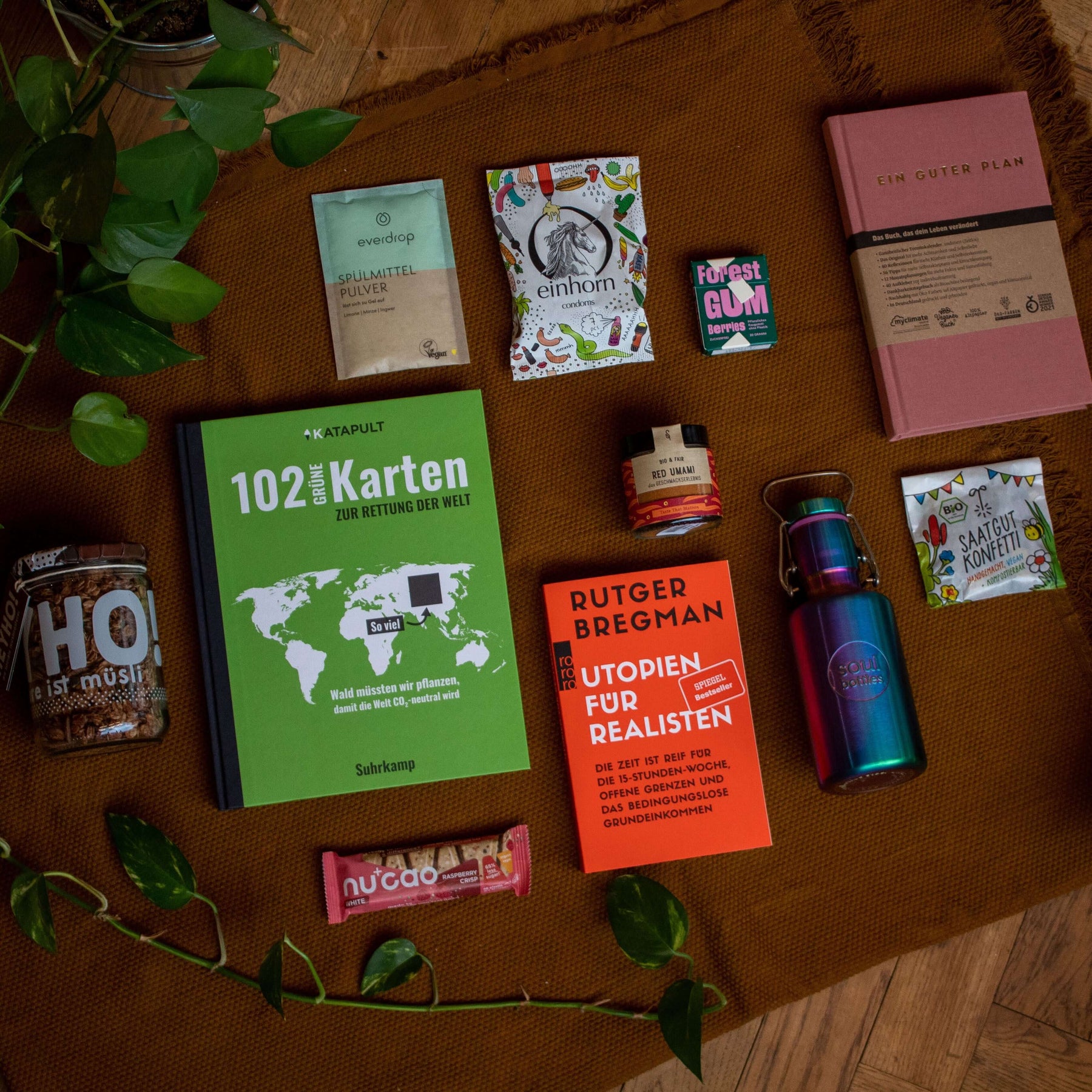 Nachhaltige Geschenke für Freunde, darunter Bücher, Snacks und umweltfreundliche Produkte auf einem Tisch.