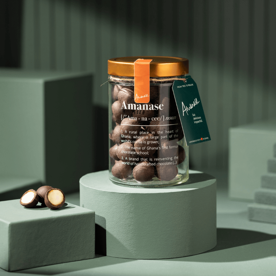 Amanase Bio-Macadamia im Glas, links zwei Macadamia-Hälften und eine ganze