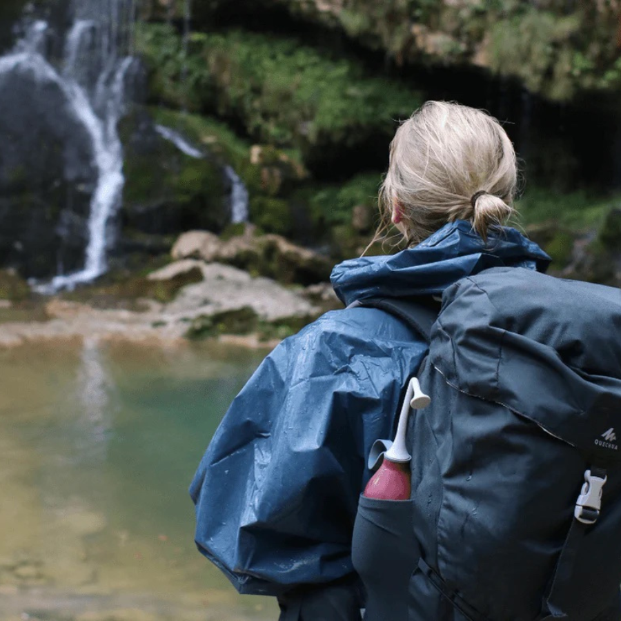 Eine Person trägt die Po- und Intimdusche von Bidetlity an der Seite von ihrem Rucksack