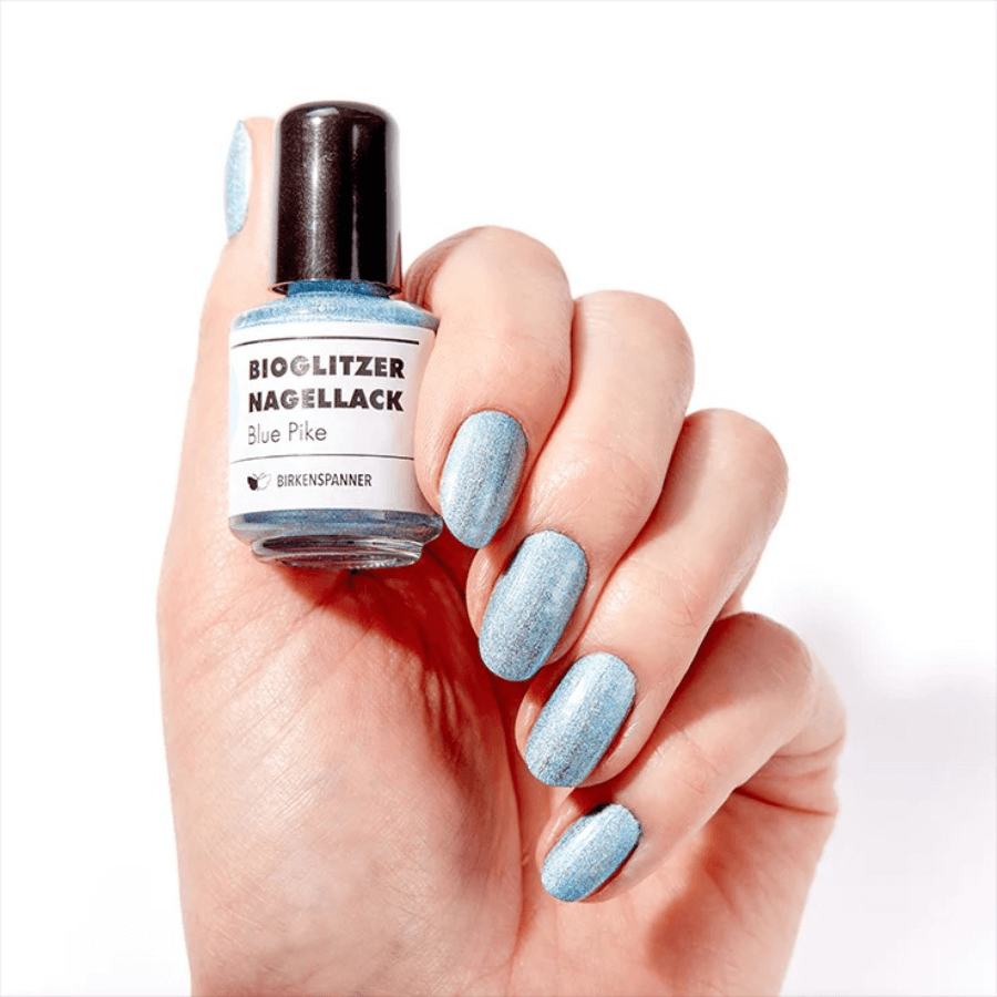 Persön hält Birkenspanner Bioglitzer Nagellack – Blue Pike in den Händen