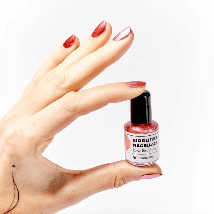 Person hält Birkenspanner Bioglitzer Nagellack Ruby Radiance in den Händen