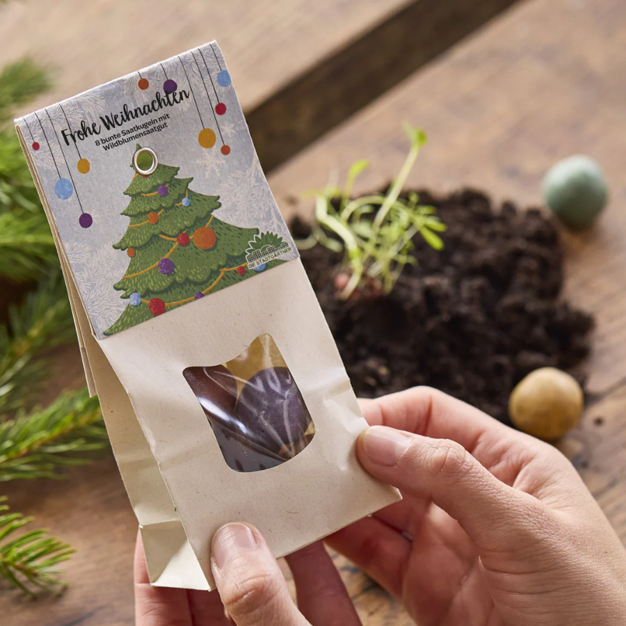 Person hält Weihnachtliche Blumenmurmeln von Die Stadtgärtner "Frohe Weihnachten" in den Händen