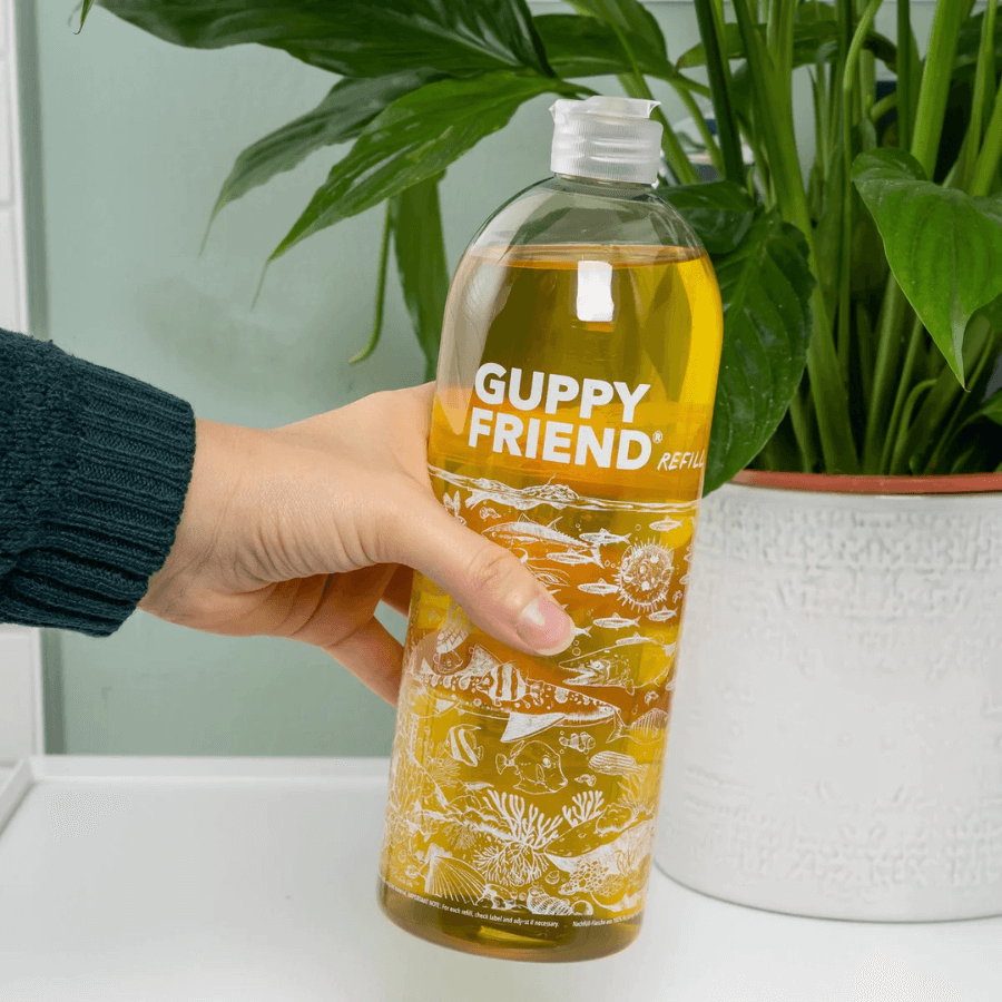 Eine Hand hält das Guppyfriend Vollwaschmittel 