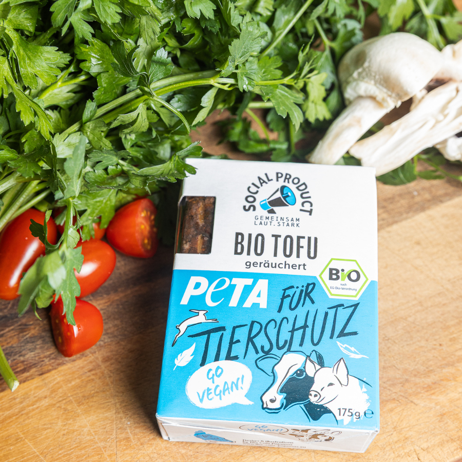 Die Bio-Tofu Verpackung von social product liegt neben Gemüse