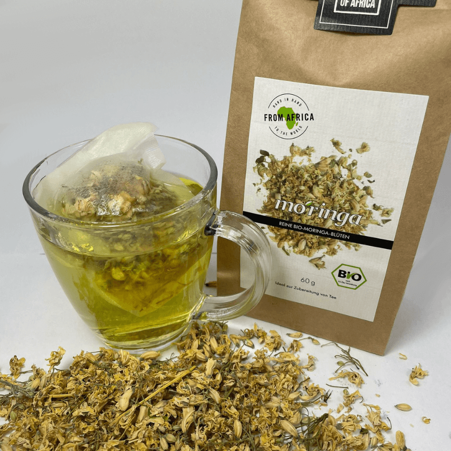 The Essence of Africa – Moringa Blüte Verpackung von vorne mit Tasse Tee und losen Blüten