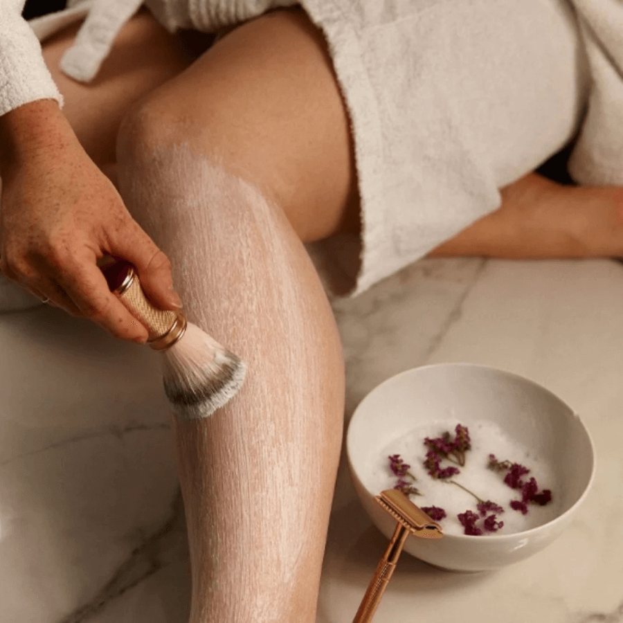 Nacktes Bein wird mit der Rasierseife eingepinselt