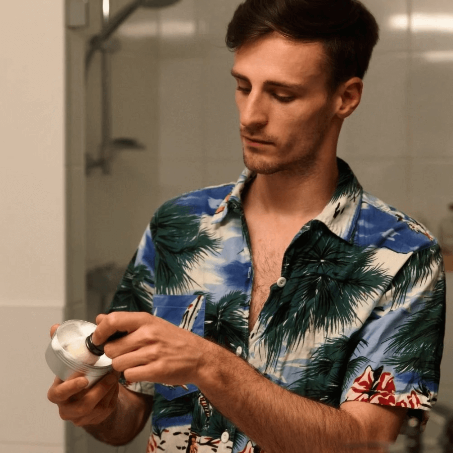 Ein Mann schäumt die Rasierseife in der Dose mit einem Pinsel auf