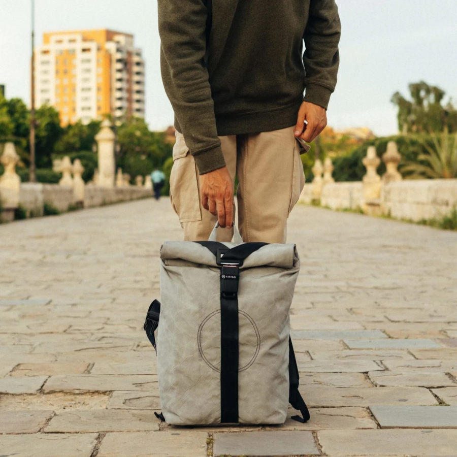Person hält den grauen Rolltop Big von airpaq vor den Füßen