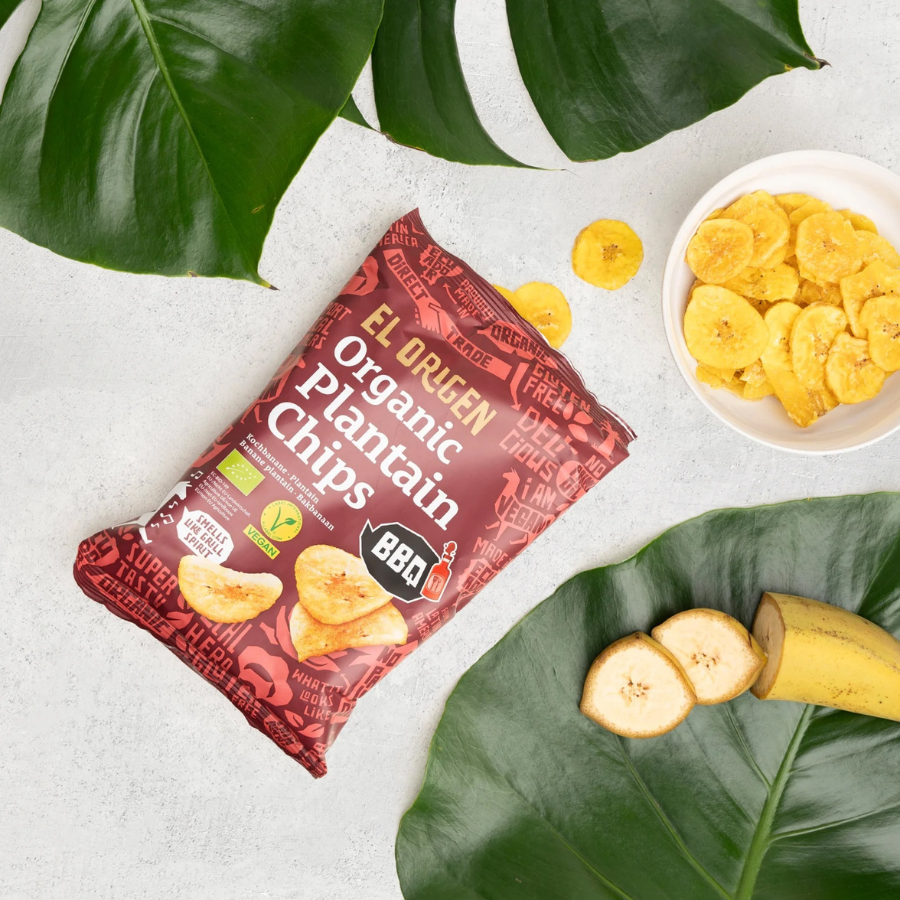 el origen Kochbanenchips mit BBQ Verpackung, daneben Blätter und eine Banane