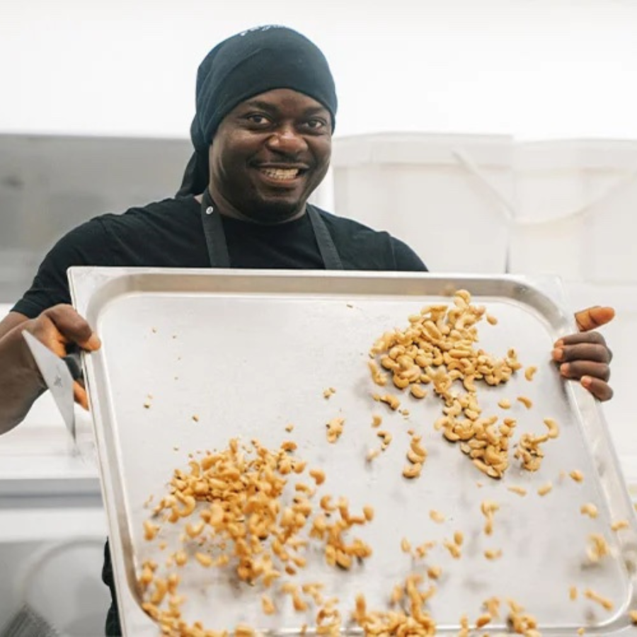 Gesalzene und geröstete Cashewkerne von fairfood auf einem Blech, gehalten von einer Person