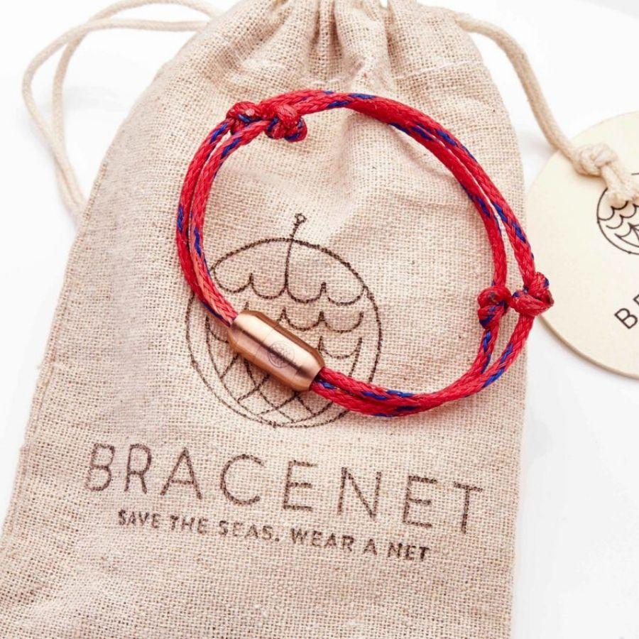 Rotes Armband mit rosegoldenem Verschluss auf Säckchen liegend