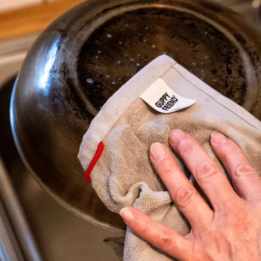 Eine Pfanne wird mit dem Spültuch abgewaschen