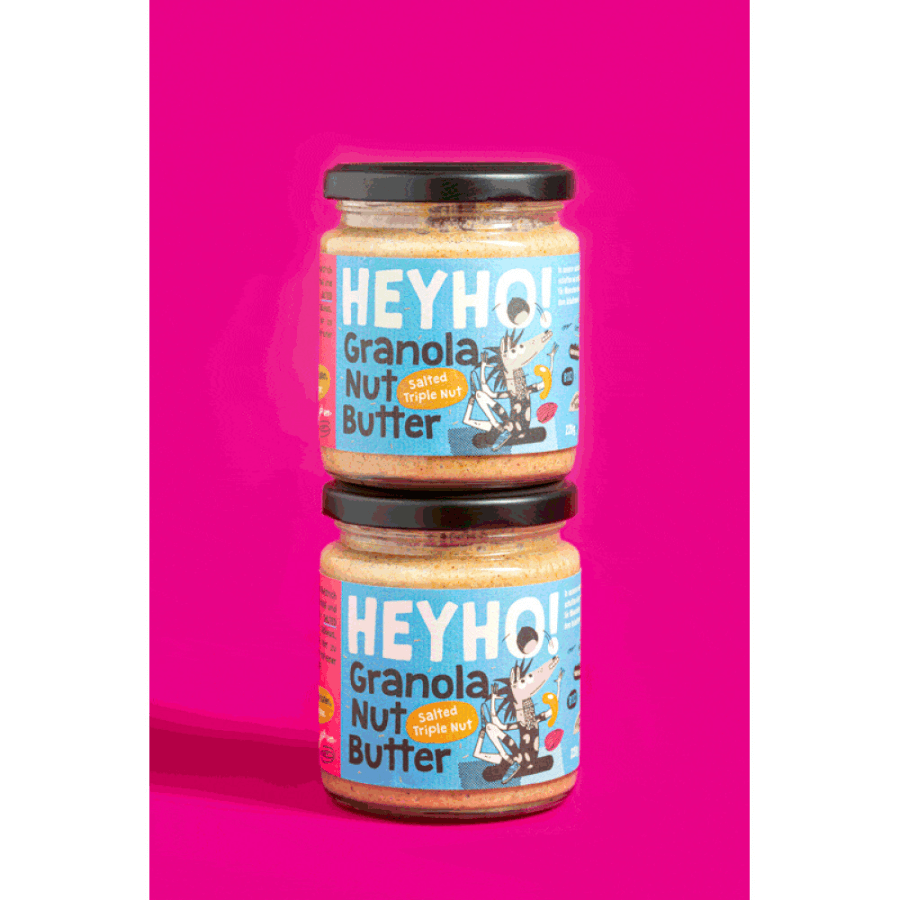 2 Gläser Heyho Granola Nussbutter Salted Tripple Nut vor pinkem Hintergrund