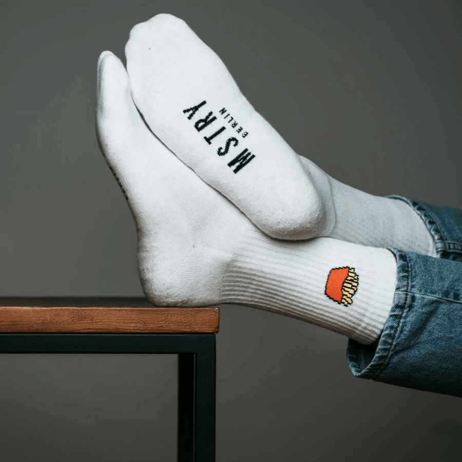 Mstry Socken Pommes am Fuß, Füße liegen auf einem Tisch