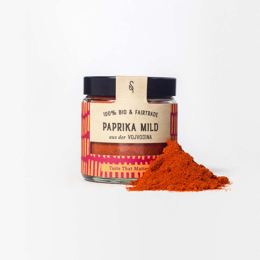 Milde Paprika in Glasverpackung mit Gewürzhäufchen von vorne