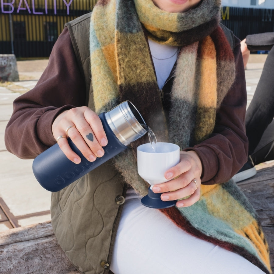 Frau schenkt aus Dopper Trinkflasche Insulated Breaker Blue in Becher