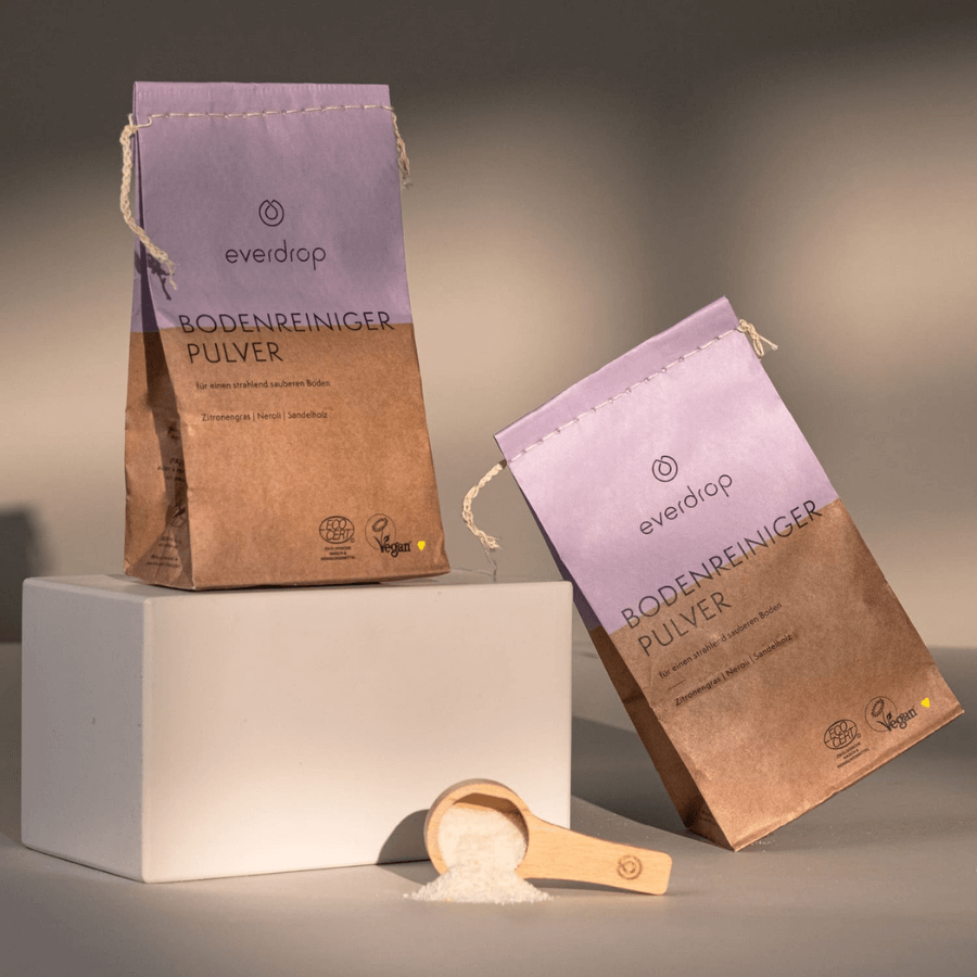 2 Verpackungen everdrop Bodenreiniger Pulver - eine seitlich, eine stehend. Mit Dosierlöffel im Vordergrund