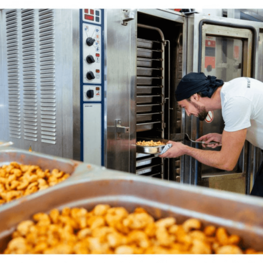 Mann stellt Tablett mit Cashews in den Ofen