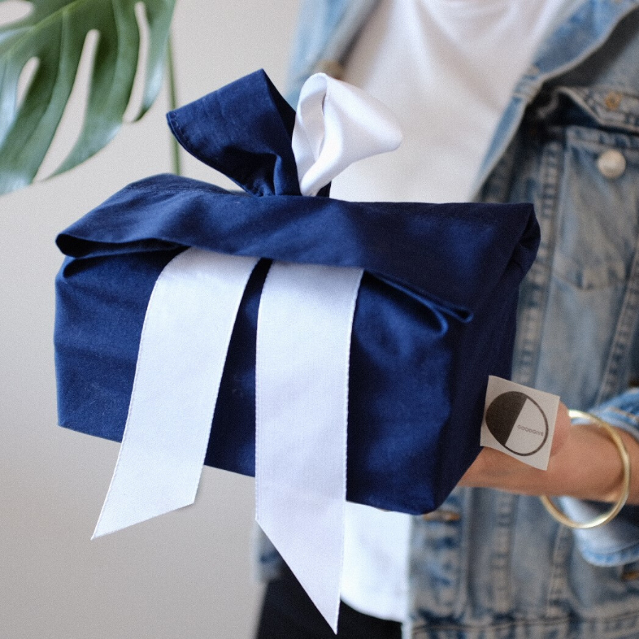 Blaues Geschenk mit weißer Schleife gehalten