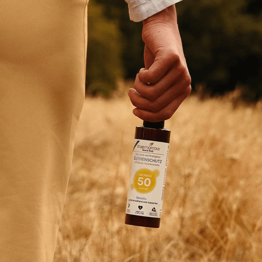 Eine Person läuft über ein Feld und hält die Sonnencreme von truemorrow in der Hand