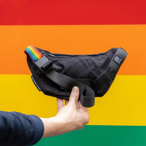 Person hält die Airpaq Hip Baq Pride vor buntem Hintergrund