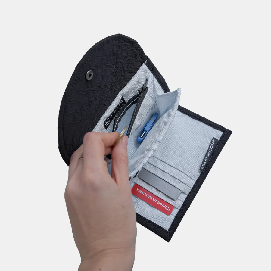 Eine Hand wirft eine Münze in die Geldbörse von Airpaq