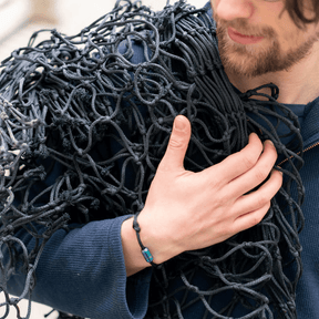 Person trägt das Bracenet Black Sea ll - bunter Verschluss und ein schwarzes Netz über der Schulter