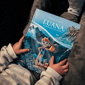 Kind halt das Kinderbuch Lund, die Bonbontüre und das Meer von Bracenet in der Hand