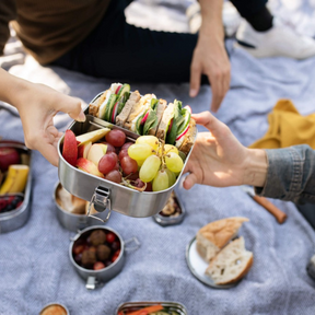 Person hällt gefüllte ECO Brotbox Bento Flex+ geöffnet  in den Händen