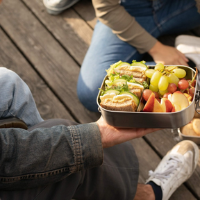 Person hällt gefüllte ECO Brotbox Bento Flex+ geöffnet  in den Händen
