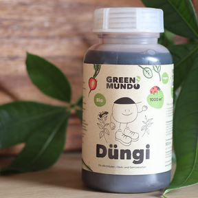 Düngi von Green Mundo – 500 ml Flasche mit Pflanze im Hintergrund