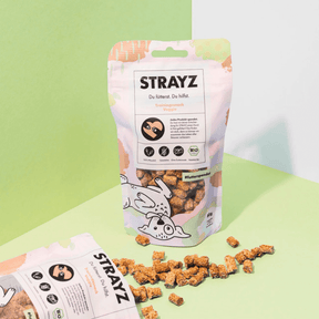 Veggie Hundesnack von STRAYZ – Verpackung von vorne und eine geöffnete Verpackung aus der Snacks rausfallen 