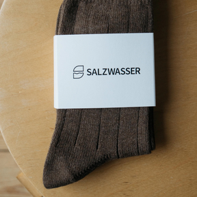 Stricksocken von Salzwasser in Braun – liegen mit Banderole auf dem Tisch