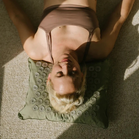 Person liegt mit dem Kopf auf dem Shakti Premium Kissen – Salbeigrün