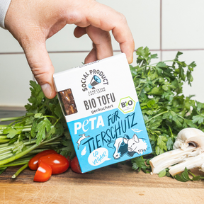 Eine Hand hält die Bio-Tofu Verpackung von social product