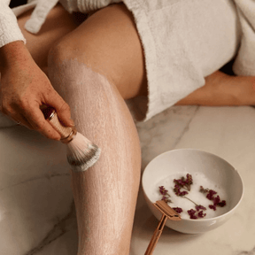 Nacktes Bein wird mit der Rasierseife eingepinselt