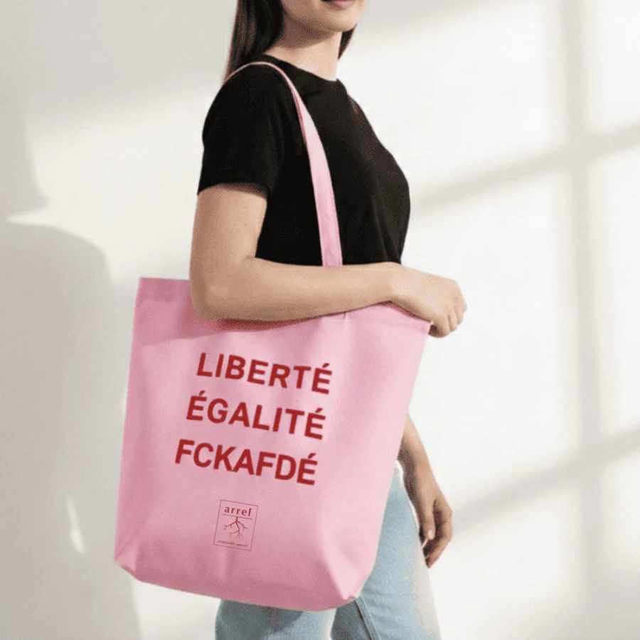 Person trägt Tote Bag – LIBERTÉ ÉGALITÉ FUCK AFD von arrel Pink mit roter Schrift 