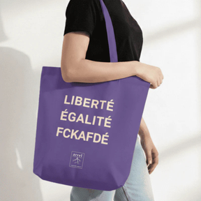 Person trägt Tote Bag – LIBERTÉ ÉGALITÉ FUCK AFD von arrel Lila mit heller Schrift 