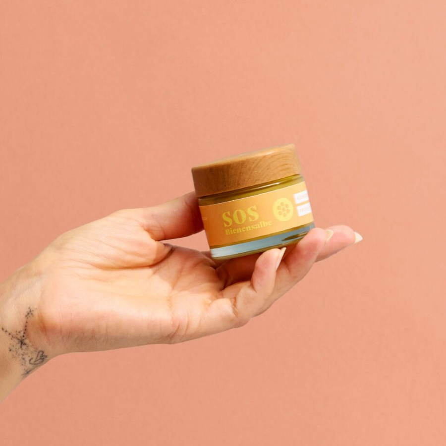Hand hält die SOS-Bienensalbe mit Propolis von forpeople