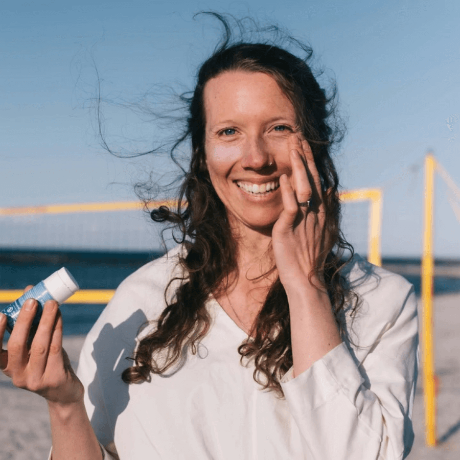 Frau benutzt 4peoplewhocare feste Sonnencreme LSF 50 am Strand
