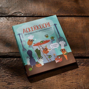 Cover des Kochbuchs AckerKüche von Ackerdemia vor hölzernem Hintergrund