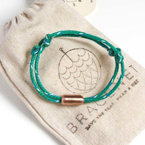 Grünes Armband mit rosegoldenem Verschluss auf Säckchen liegend