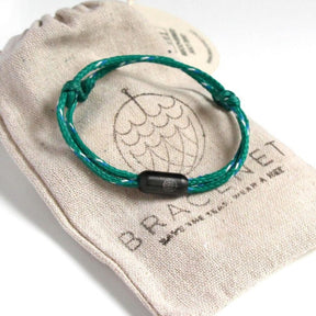 Grünes Armband mit schwarzem Verschluss auf Säckchen liegend