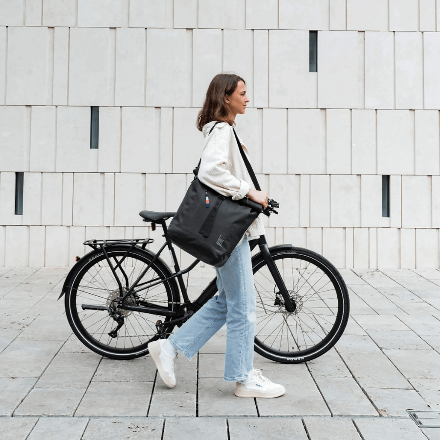 Frau schiebt ihr Fahrrad und hat die Got Bag Bike Bag um die Schulter hängen