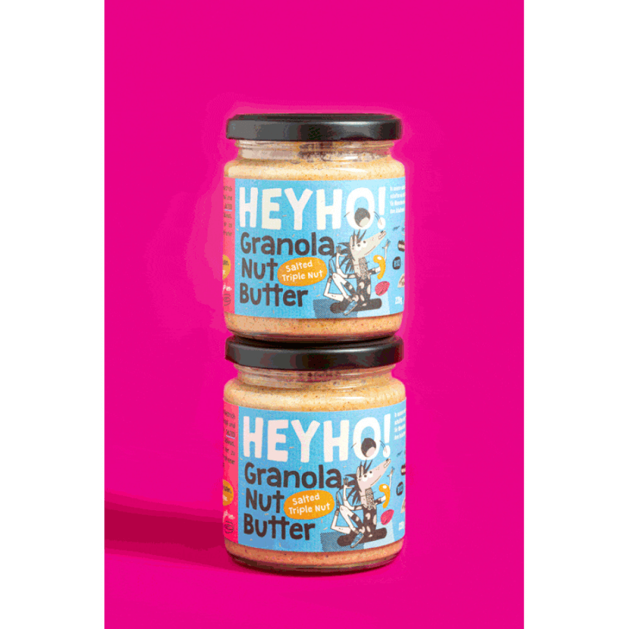 2 Gläser Heyho Granola Nussbutter Salted Tripple Nut  vor pinkem Hintergrund