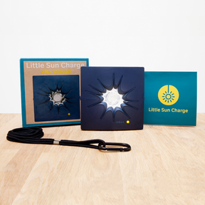 Verpackungsinhalt der Little Sun Charge Solar Powerbank, bestehend aus einer Box, der Powerbank und einem Umhängeband mit Karabiner. 
