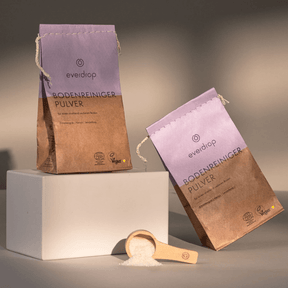 2 Verpackungen everdrop Bodenreiniger Pulver - eine seitlich, eine stehend. Mit Dosierlöffel im Vordergrund