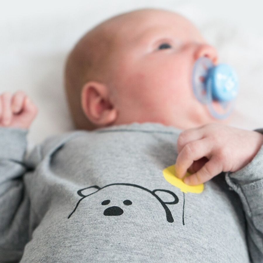 Baby in grauem Body mit Bär-Motiv