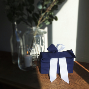 Blaues Geschenk mit weißer Schleife auf Tisch