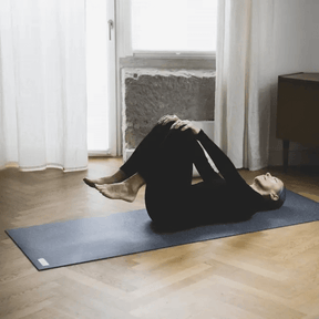 Frau liegt auf dem Rücken auf der dunklen Yogamatte